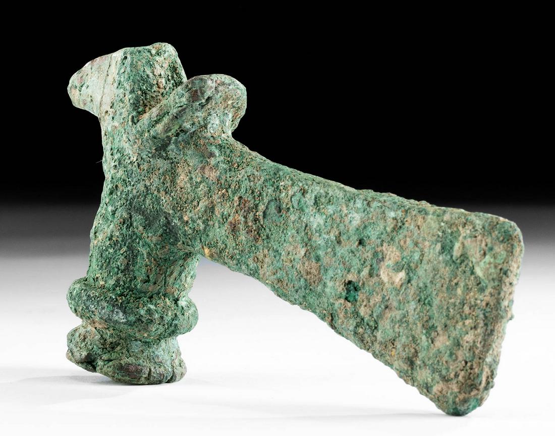Luristan Copper Socketed Axe Head: **First Time At Auction** Ancient Near East, northwestern Iran, Luristan, ca. 1000 to 600 BCE. A cast-copper axe head of a sturdy form. The vertical blade protrudes outwards in front of the cylindrica