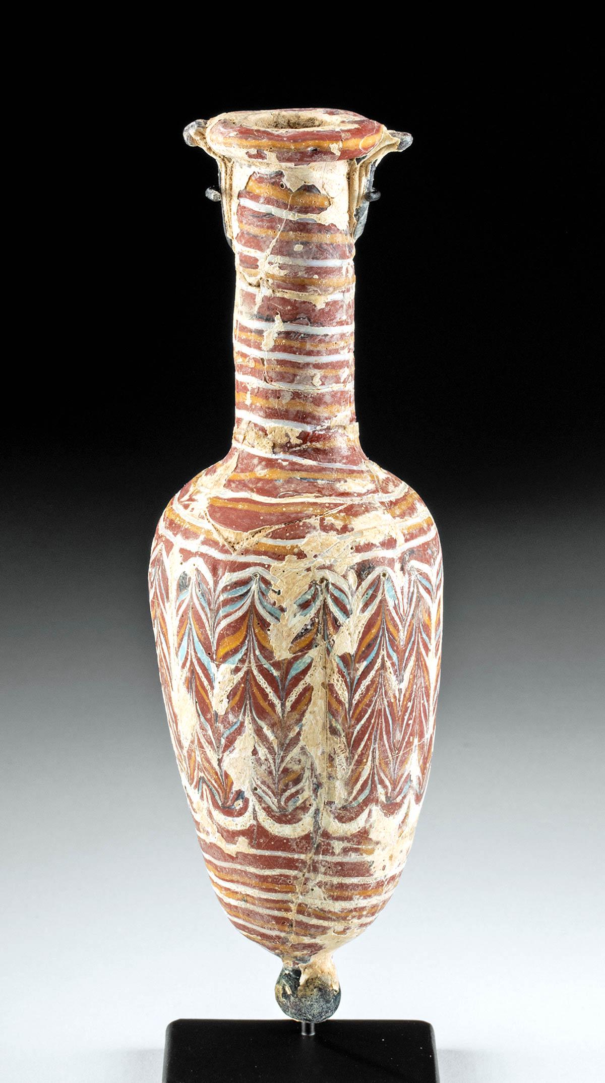 Greek Hellenistic Core Formed Glass Amphoriskos: Ancient Greece, Hellenistic Period, ca. 3rd to 1st century BCE. A lovely example of a core-formed glass amphoriskos, a miniature amphora, with gorgeous polychrome hues. The body is a piriform shape wi