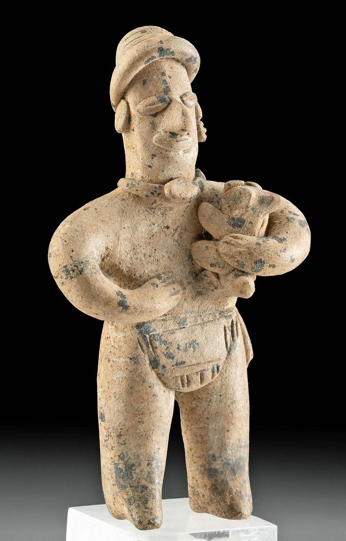 Exhibited Colima Terracotta Figure Holding Dog: Pre-Columbian, West Mexico, Colima, ca. 300 BCE to 300 CE. A charming handmade pottery figure with his proper left arm wrapped around a petite dog and his right hand placed on his flat stomach. Displa