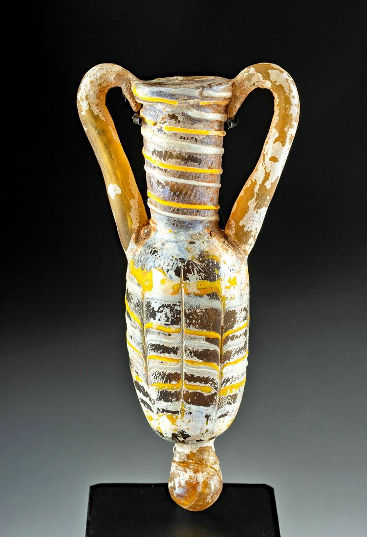Greek Hellenistic Core-Formed Glass Amphoriskos: Ancient Greece, late Hellenistic Period, ca. 2nd to 1st century BCE. A gorgeous core-formed glass amphoriskos of a narrow, elegant form. The vessel presents with a lozenge-shaped body, a rounded shoul