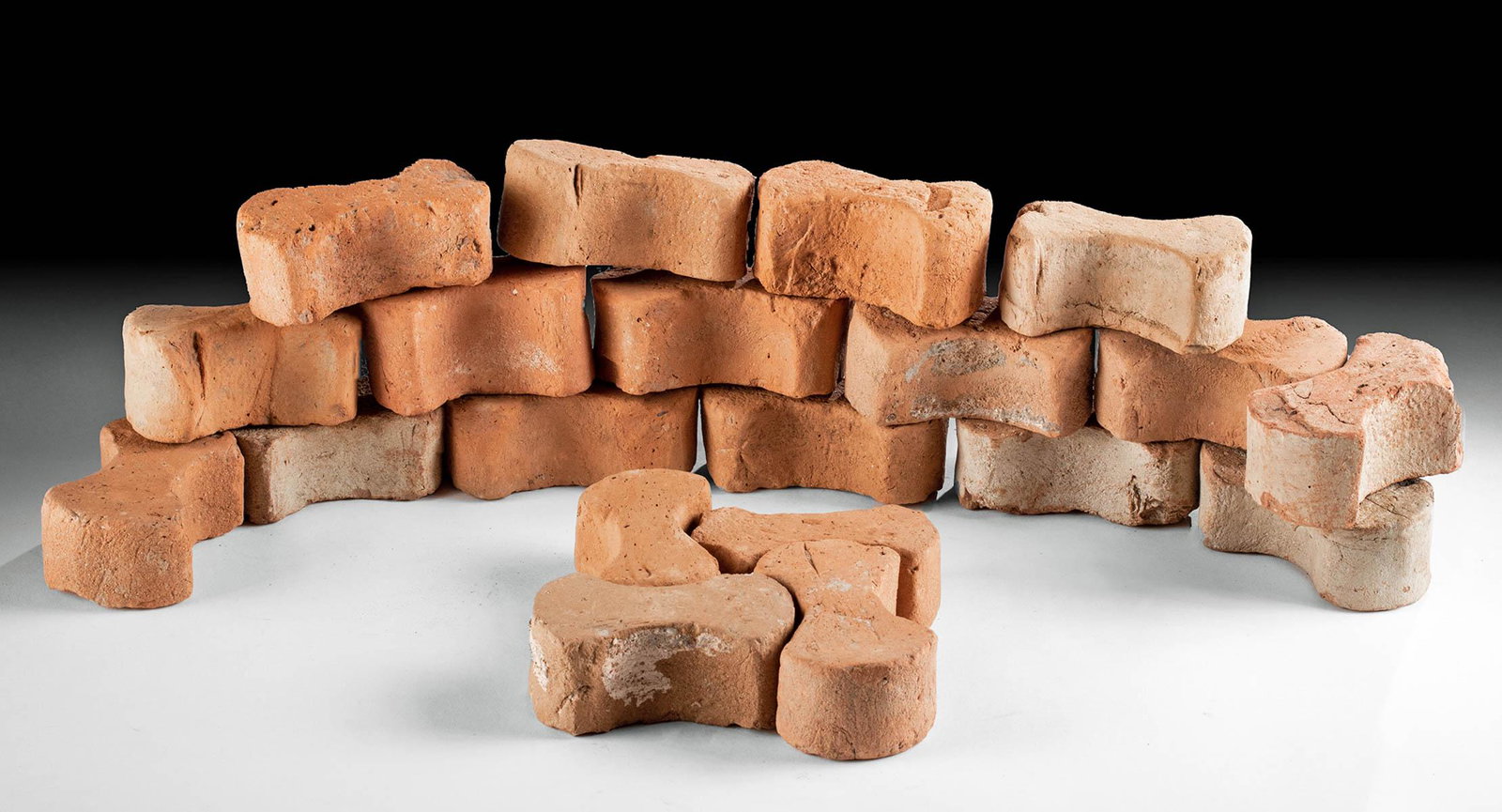 Roman Terracotta "Dog Bone" Tiles, 20 pcs: Roman, Imperial Period, ca. 1st to 2nd century CE. A wonderful gathering of twenty dog bone shaped paving tiles used to line the paths of ancient Rome. Each tile is comprised of two curved and flared 