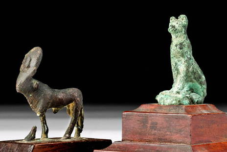 Egyptian Bronze Cat + Apis Bull, ex Parke-Bernet: Egypt, Late Dynastic to Ptolemaic Period, ca. 664 to 30 BCE. A striking pair of cast-bronze figures from ancient Egypt; a cat and an Apis bull. Seated upon its plump haunches with its sinuous tail