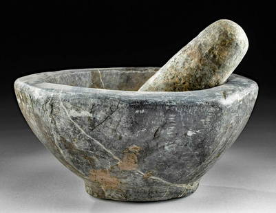 6th C. Byzantine Stone Mortar & Pestle: Near East / Holy Land, Byzantine Empire, ca. 6th to 10th century CE. A massive stone mortar with a thick grinding pestle. The hefty bowl rests on a small foot, and the thick walls lend weight to the m