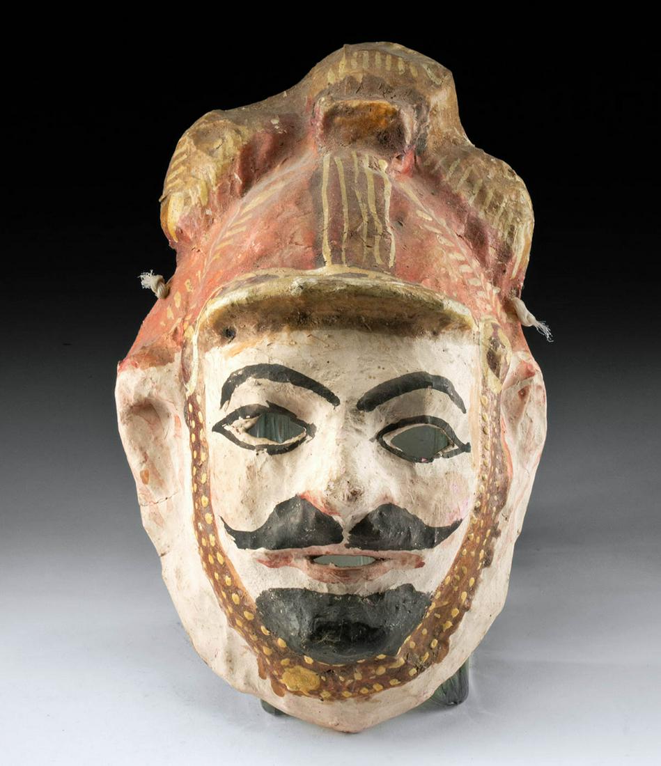 Vintage Guatemalan Plaster Festival Mask: **First Time At Auction** Central America, Guatemala, ca. early to mid 20th century CE. A hand-made papier-mache mask of a mustachioed man’s face with an ornate cap. The mask has cut-outs for the ey