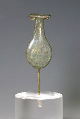 Roman Glasss Flask-Shaped Tear Vial: Ancient Roman Glass Tear Vial in flask shape, miniature form. Base flattened in an almost lozenge shape, rim everted. Pleasant green color with areas of silvery iridescence. 1-5/8"L x 5/8"W at rim. Pr