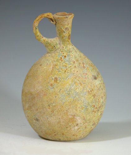 Roman Glass Ovoid-Form Bottle: Ca 3rd to 4th century AD, manufactured in the eastern Roman Empire. Freeblown, ovoid blue-green glass bottle with applied handle. 4-5/8"H.