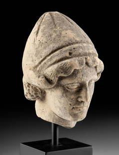Greek Terracotta Head of a Youth Wearing Pilos Helmet: Magna Graecia, South Italic Colonies, early Hellenistic, ca. 5th to 4th century CE. A handsome mold-made pottery head of a youth wearing a pilos or pileus, the traditional pointed helmet worn by the