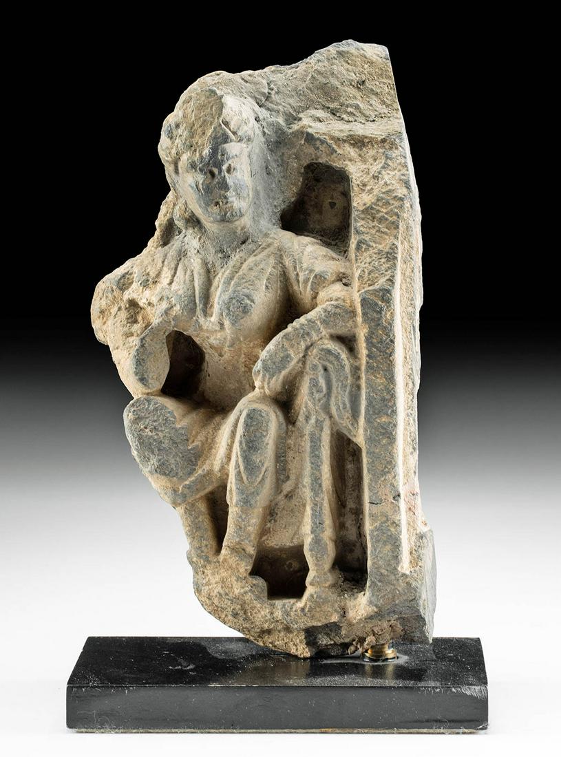 Gandharan Schist Relief of Seated Female Figure: Central Asia, Northwest Pakistan, Gandharan Empire, ca. 2nd to 3rd century CE. A fabulous carved grey schist sculpture of a seated woman. Draped in a long robe, the fascinating figure displays a slend