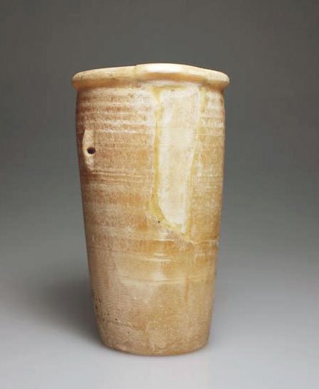 An Egyptian Alabaster Beaker: Early Dynastic, 1st-2nd Dynasty, 2920-2649 B.C. Tall, horizontally-veined cylinder beaker with two pierced lug handles on either side, has thick, concave sides that taper toward the base. The slightly
