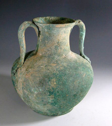 A Large Roman Bronze Amphora: Ca. 3rd to 4th century A.D. Solid bronze vessel with large bulbous base and thin, straight neck with lightly flaring rim; two epicanthus leaf handles attached opposite each other and low ring base. 7"