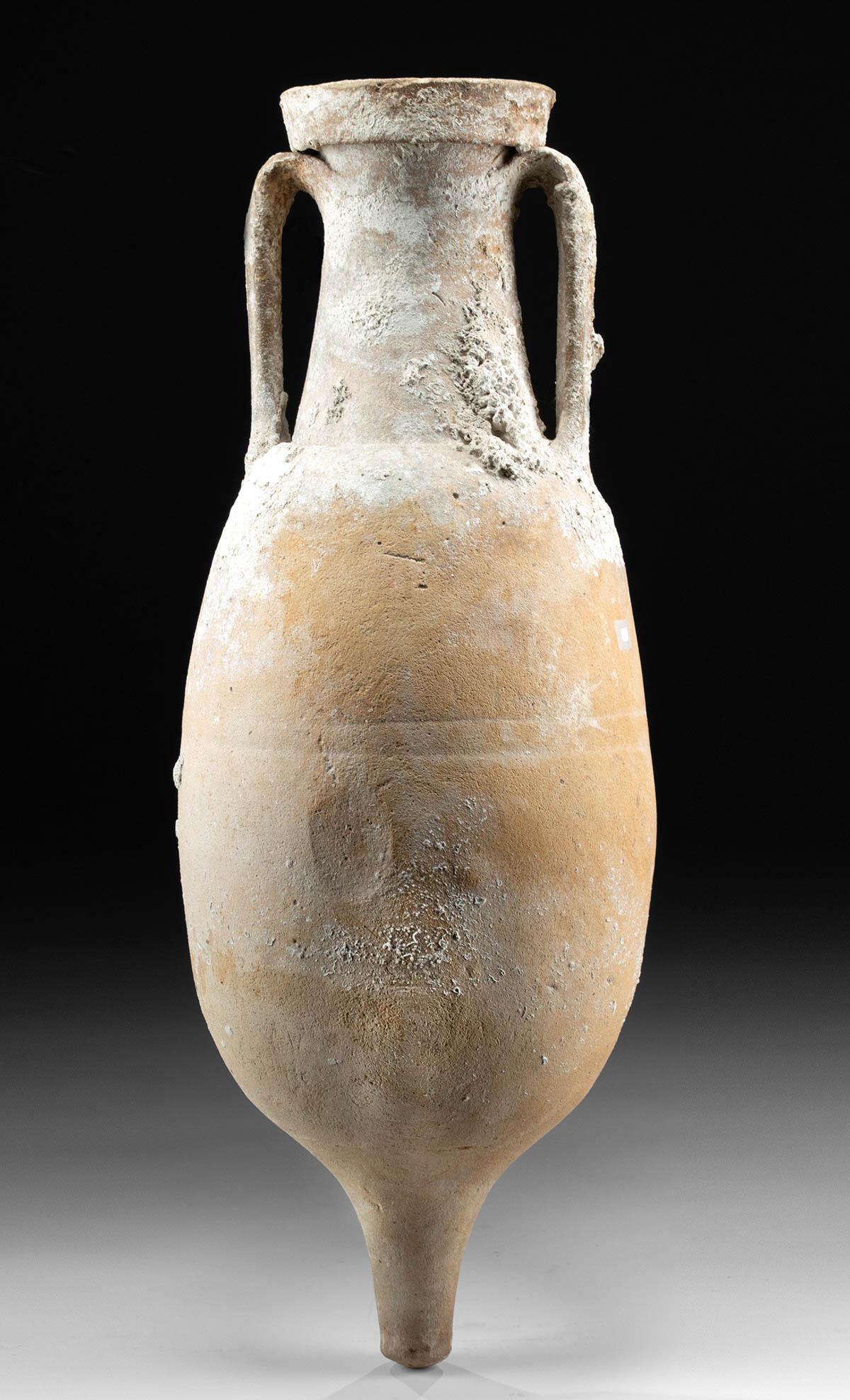 Large Roman Pottery Transport Amphora w/ Barnacles: Roman, Imperial Period, ca. 2nd to 4th century CE. A sizable, wheel-thrown pottery transport amphora with a slender nubbin base, a globular body with relatively smooth surfaces, a gently tapered neck,
