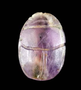 Petite Egyptian Middle Kingdom Amethyst Scarab Bead: Ancient Egypt, Middle Kingdom, 11th to 13th Dynasty, ca. 2130 to 1649 BCE. A dainty scarab bead with a central suspension perforation, hand-carved from mottled purple amethyst with streaky white