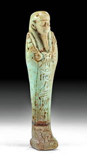 Translated Egyptian Faience Ushabti for Hor-Sam-Tawy: Egypt, Late Dynastic Period, 26th to 31st Dynasty, ca. 664 to 332 BCE. A mold-formed faience ushabti covered in lustrous green glaze. The figure presents in mummiform atop an integral plinth, holds a