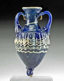 Greek Core-Formed Glass Amphoriskos: Ancient Greece, ca. 6th to 4th century BCE. A beautiful example of a core-formed glass amphoriskos once used to hold aromatic oils. The vessel boasts an elegant form with a piriform body that is