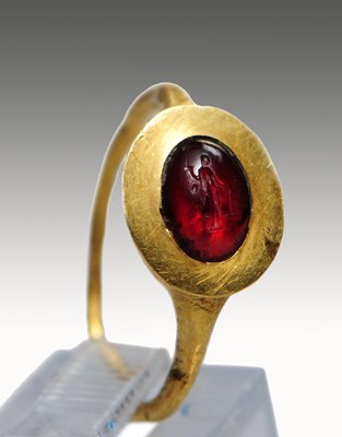 A Roman Gold and Garnet Intaglio Ring: Rome, ca. 1st-3rd Century A.D. Plain gold hoop, the wide bezel set with a garnet intaglio engraved with Fortuna. Ring size 2. Provenance: Christie's, Ancient Jewelry Sale 2233, 11 December 2009 lot 40
