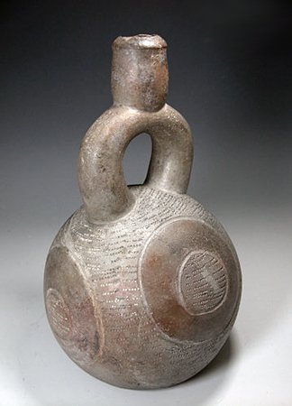 A Chavin Decorated Stirrup Bottle: From ancient Peru, Chavin culture, ca. 200 B.C. Grayware pottery stirrup vessel with bulbous body decorated with four large round disc type elements. Textured background and interior centers of each d