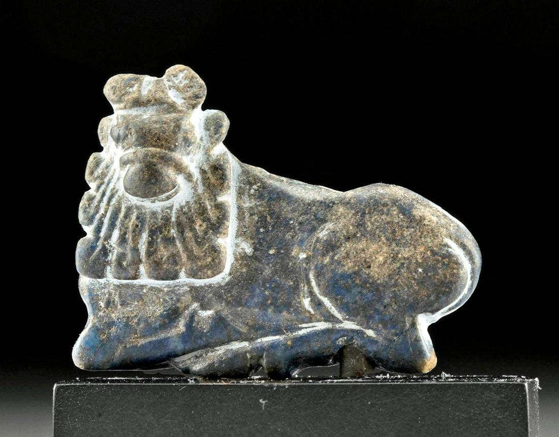 Rare Sumerian Lapis Lazuli Recumbent Bull Pendant: Ancient Near East, Mesopotamia, Sumer, ca. 2700 to 2000 BCE. A beautiful and petite example of a hand-carved lapis lazuli bull pendant exhibiting mottled blue, cream, and honey yellow hues. The flat-f