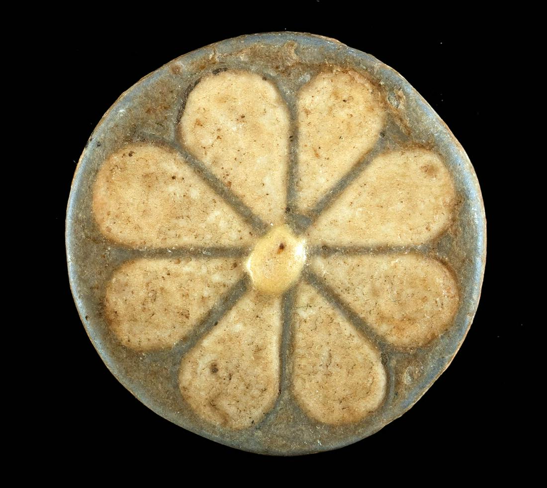 Egyptian New Kingdom Faience Rosette Tile: Ancient Egypt, New Kingdom, 20th Dynasty, ca. 1189 to 1077 BCE. A fine faience tile of a discoid form exhibiting a delicate rosette flower that was perhaps an inlaid ornament in a home or pharaonic pa