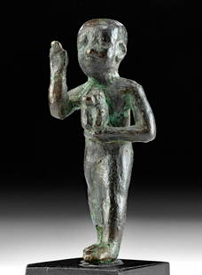 Egyptian Bronze Priest Holding a Baboon: Ancient Egypt, Saite Period, Twenty-Sixth Dynasty (XXVI), ca. 664 to 525 BCE. A very rare cast bronze figure of a standing priest, bald, wearing a long skirt/kilt, and raising one hand as if in blessi