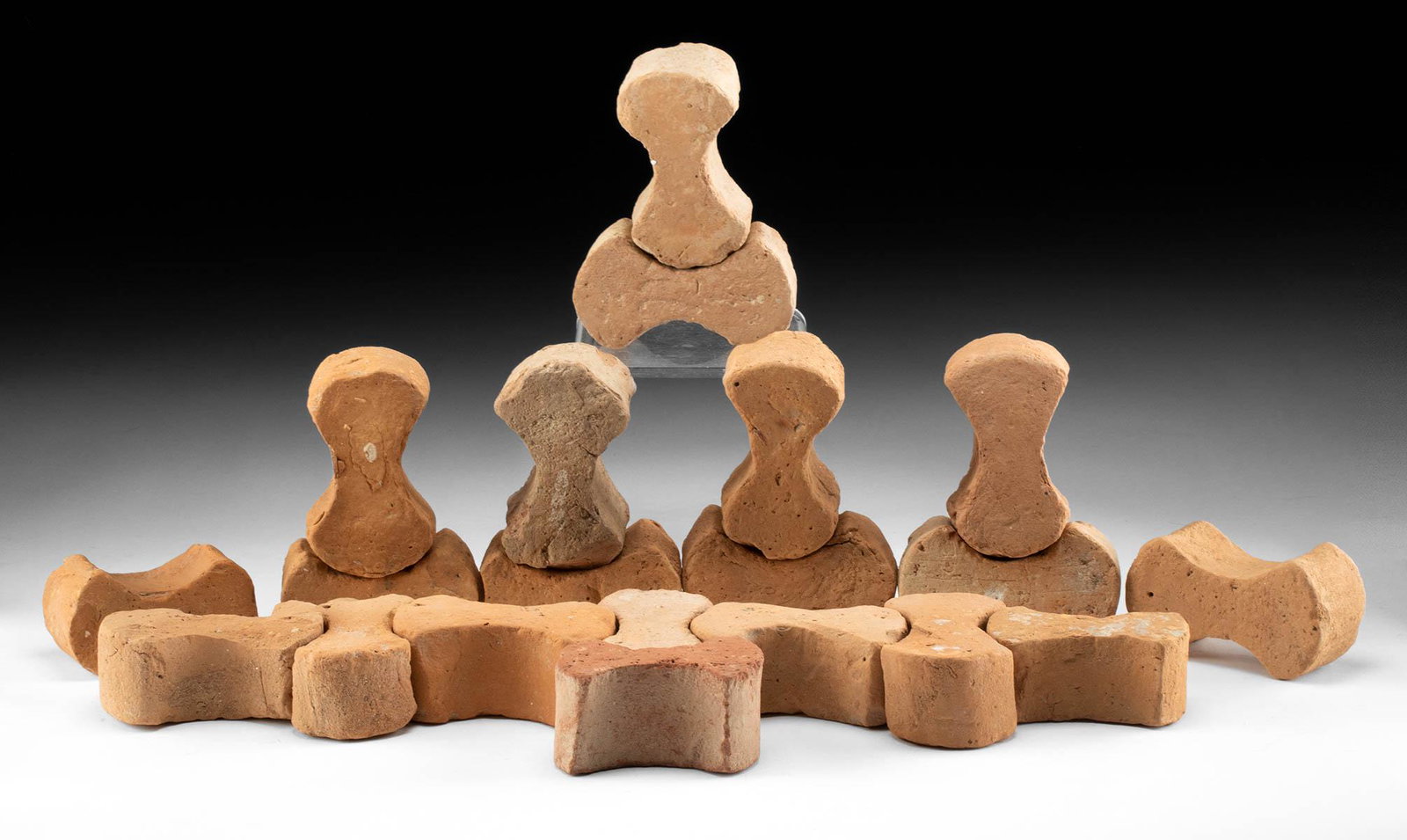 20 Roman Terracotta "Dog Bone" Tiles: Roman, Imperial Period, ca. 1st to 2nd century CE. A fantastic ensemble of 20 terracotta paving tiles shaped in a 'dog bone' form, used to line the paths of ancient Rome. Each tile is comprised of two