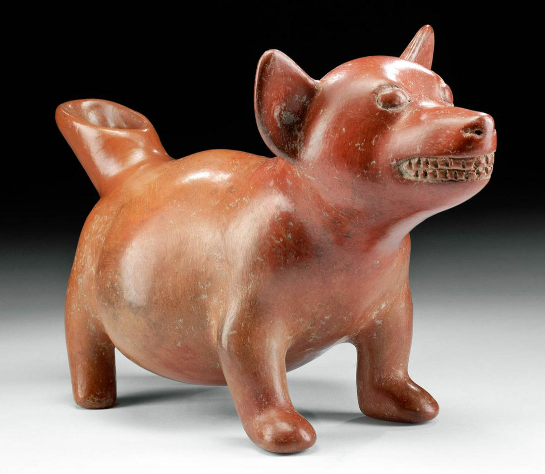Charming Colima Redware Effigy Dog Vessel: Pre-Columbian, West Mexico, Colima, ca. 300 BCE to 300 CE. A hand-built and highly burnished redware pottery vessel in the shape of an adorable dog. The charming canine presents standing atop a quarte
