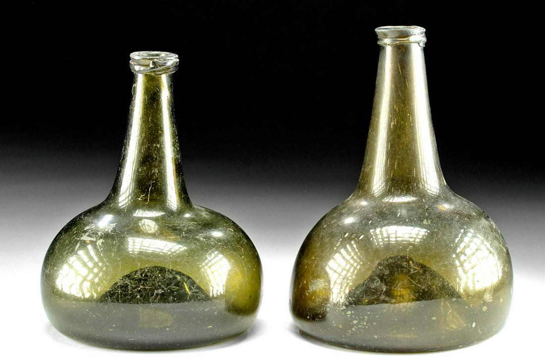 18th C. Dutch / USA Glass Onion Bottles (pr): Western Europe, The Netherlands or Belgium, or United States, ca. 18th century CE. A lovely pair of mouth-blown onion glass bottles in a dark amber-green hue. These bottles have the characteristic oni