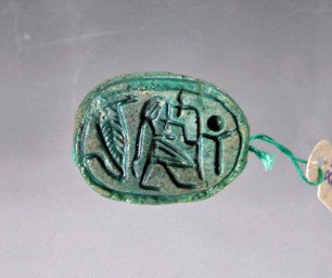 An Egyptian Steatite Scarab - Uraeus: From ancient Egypt, found in Abydos, XII Dynasty 1991-1786 B.C., Middle Kingdom. Green glazed steatite scarab, showing a man or prince (official of some type) carrying a symbol of power (sceptre or wa