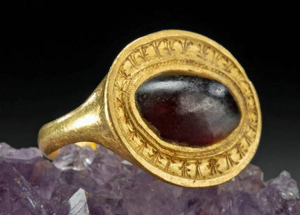 Greek Gold Ring Garnet Cabochon, ex-Christie's: Ancient Greece, late Classical to early Hellenistic period, ca. 4th century BCE. A fabulous 95% gold (equivalent to 22K+) ring with a garnet stone set into the discoid face. A thin ovoid band widens