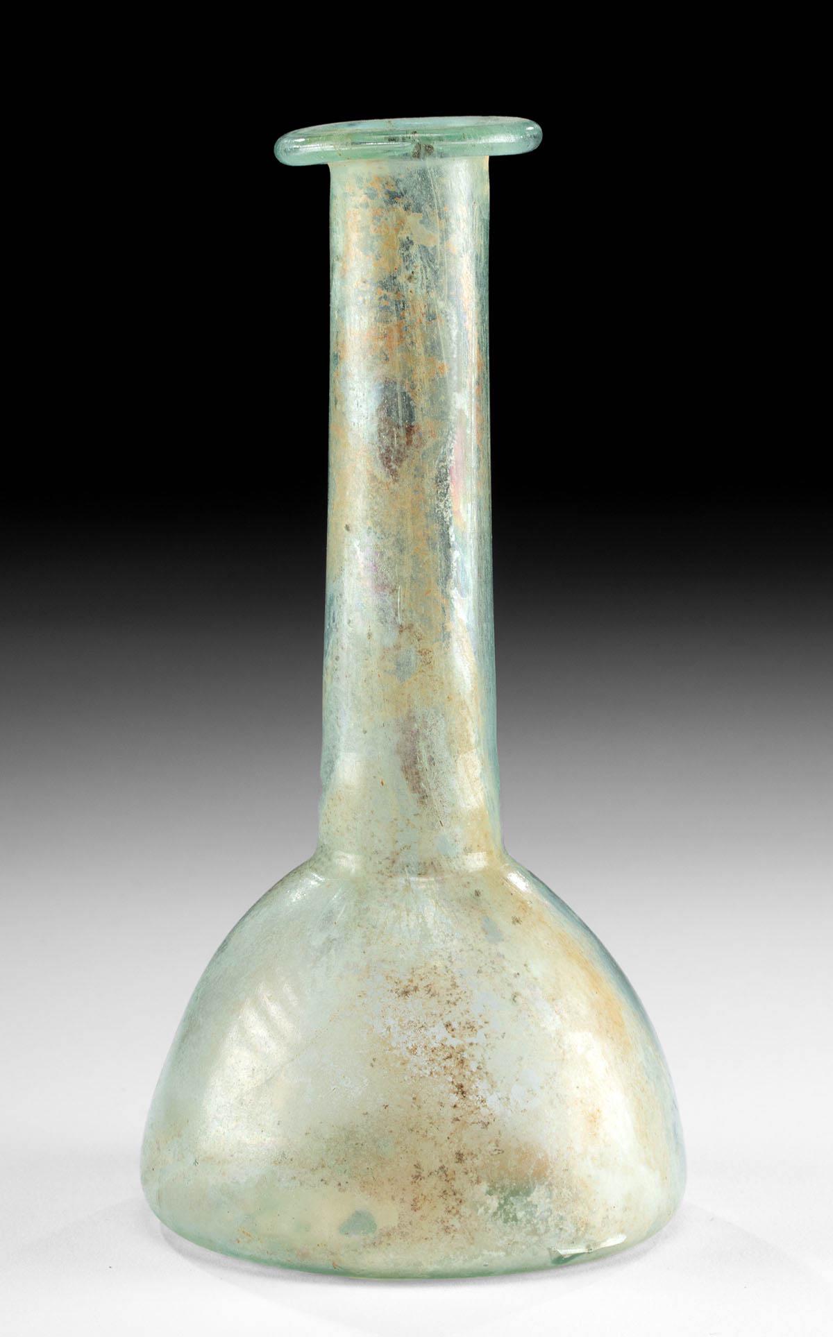 Tall Roman Glass Flask: Roman, Imperial Period, ca. 1st to 3rd century CE. A tall example of a flask that is free blown from nearly transparent glass in soft turquoise hues. The vessel exhibits a hemispherical, bell-shaped b