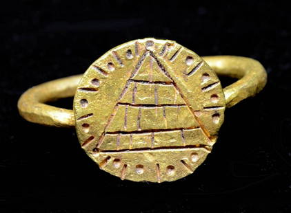 Rare Egyptian Ptolemaic Gold Ring Stylized Pyramid: Egypt, Ptolemaic Period, ca. 332 to 30 BCE. A hand-built 22K gold ring of wearable form with a circular face incised with a stylized pyramid surrounded by radiating lines and petite dots. The