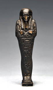 Egyptian Dark Glazed Faience Ushabti: Egypt, Late Dynastic to Ptolemaic Period, ca. 4th to 3rd century BCE. A fine ushabti figure formed from faience that stands in mummiform atop an integral rectangular plinth with a T-shaped