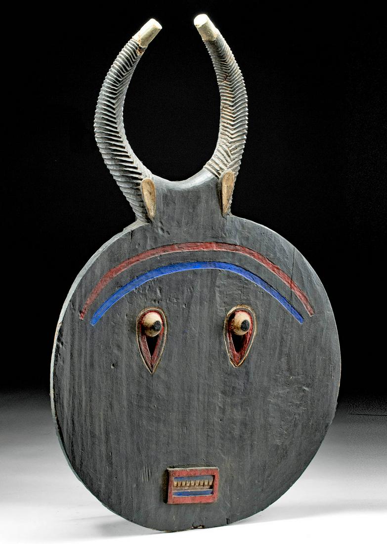Massive African Baule Painted Wood Kplekple Goli Mask: **Originally Listed At $1200** West Africa, Ivory Coast, Baule, ca. early to mid-20th century CE. A remarkably massive wooden mask of discoid form capped by a tremendous pair of curved horns, each dee