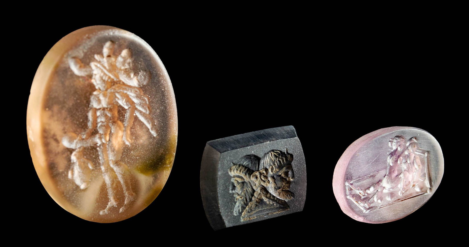 Three Neoclassical Intaglios: **First Time At Auction** Europe, 19th to mid 20th century. Three finely executed stone intaglios of various scenes. First is a carve brownish/pule amethyst intaglio showing an Ithyphallic god wearing