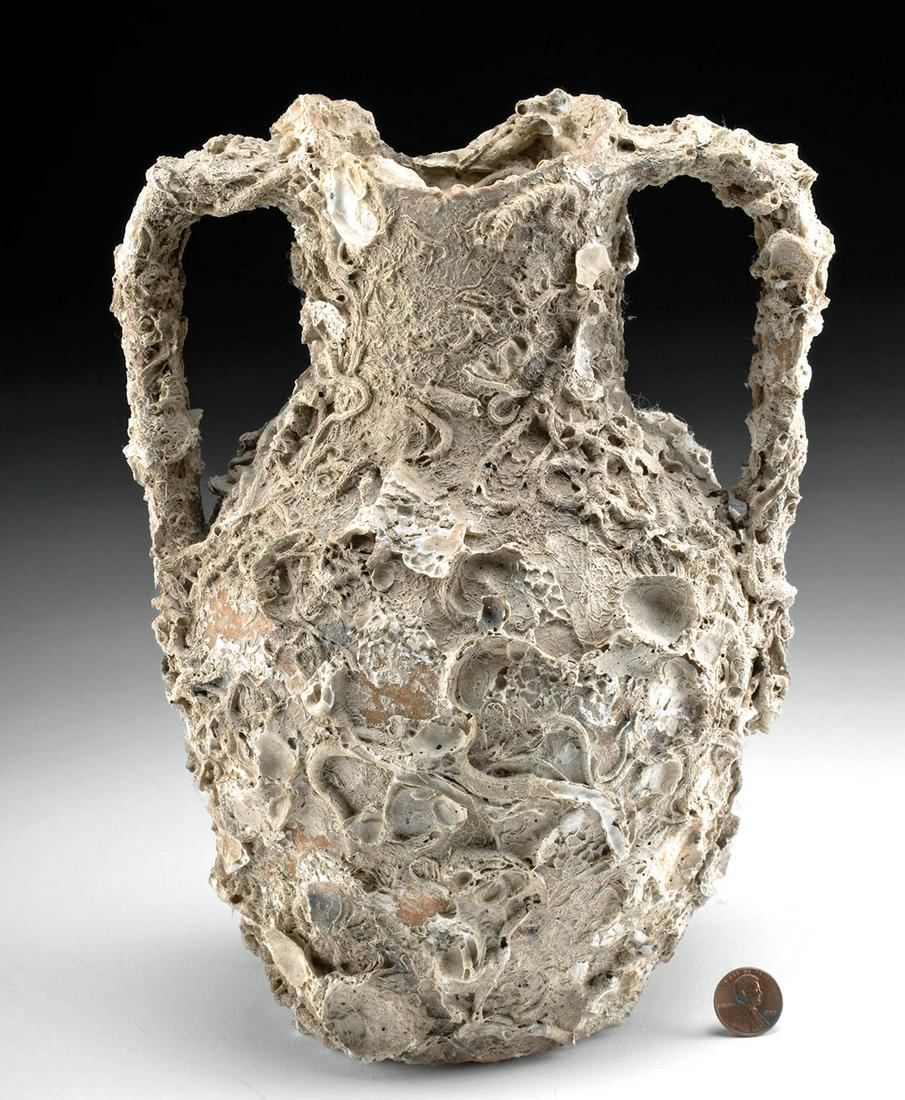 Roman Pottery Transport Amphora w/ Marine Encrustations: Roman, Imperial Period, ca. 2nd to 4th century CE. A quintessential terracotta transport amphora enveloped in extensive oceanic encrustations from centuries spent in the depths of the sea. The wheel-t