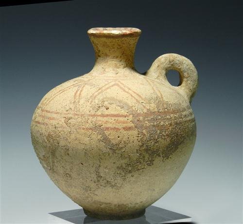 Cypriot Terracotta Vessel with Ring Handle: Cyprus, late 2nd / early 1st millenium BC. Buff terracotta round bellied jug decorated with a brown geometric pattern, ring-shaped carrying handle and narrow mouth. 6-1/4"H x 5-3/8"D at widest. Proven