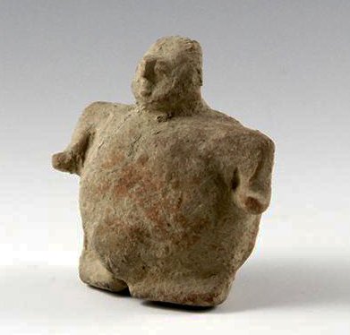 A Colima Rattle Figure, Pre-Columbian West Mexico: Circa 200 B.C. – 200 A.D. This Colima rattle figure measures approximately 3” tall by about 3” wide, and depicts a rotund female figure. She is shown in a seated position, with arms gracefully c