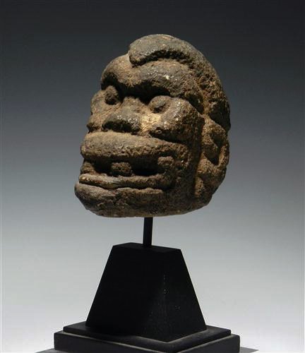 A Pre-Columbian Costa Rican Stone Head: Ca 800 to 1200 AD. Basalt stone head in the form of an angry looking monkey. Deep set features including very ferocious fangs. Custom mounted. 4" L. Provenance: Ex-Brian Saldano Collection This lot wi