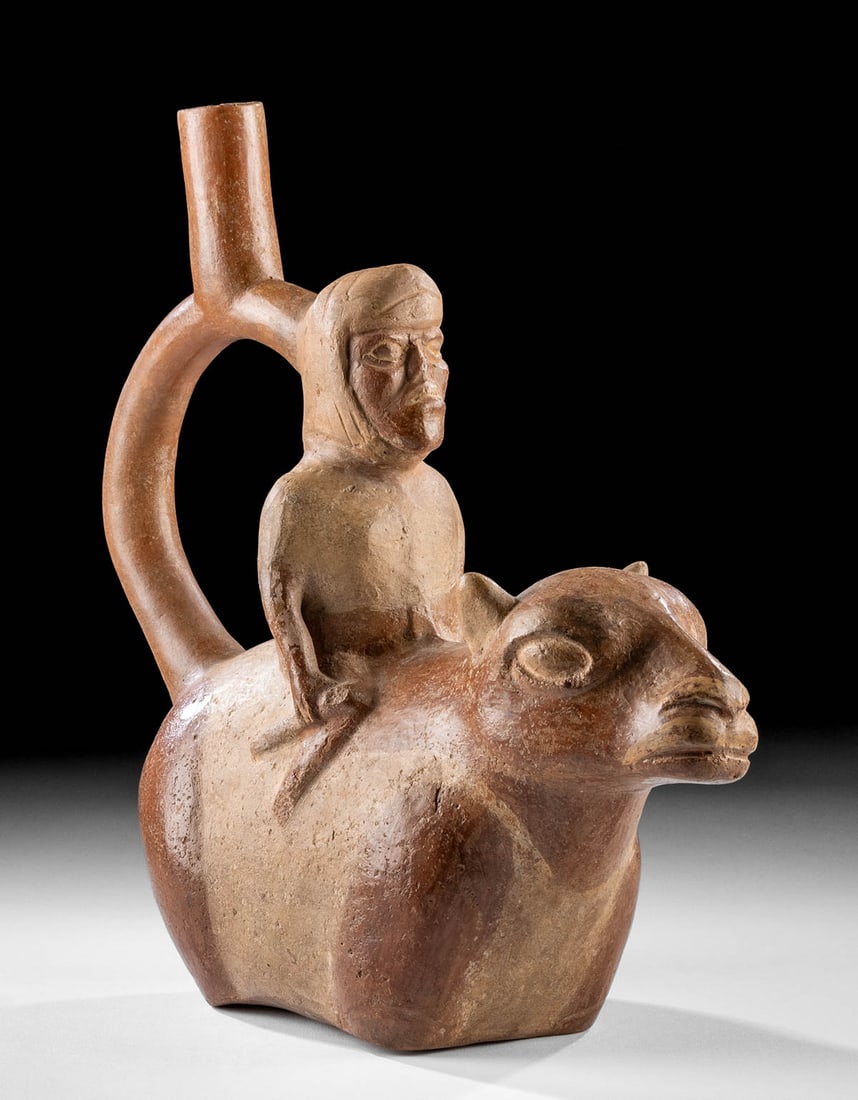 Moche Stirrup Vessel - Llama w/ Diseased Rider: Pre-Columbian, Northern Coast Peru, Moche, ca. 500 to 700 CE. A fascinating stirrup vessel, mold-formed into a llama or alpaca with a disfigured rider. The man's nose and lips are eaten away from an i