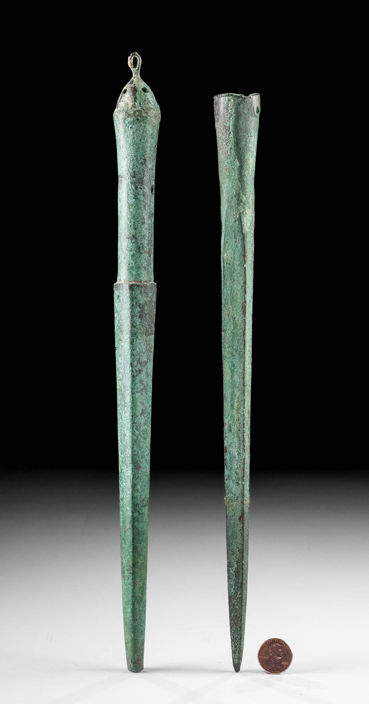 Ancient Luristan Bronze Spear Butts: Ancient Near East, Northwestern Iran, Luristan, ca. 1200 to 800 BCE. A set of 2 cast-bronze spear butts, each with a stocky lower spike. The first spear butt features an open socketing shaft of cylind