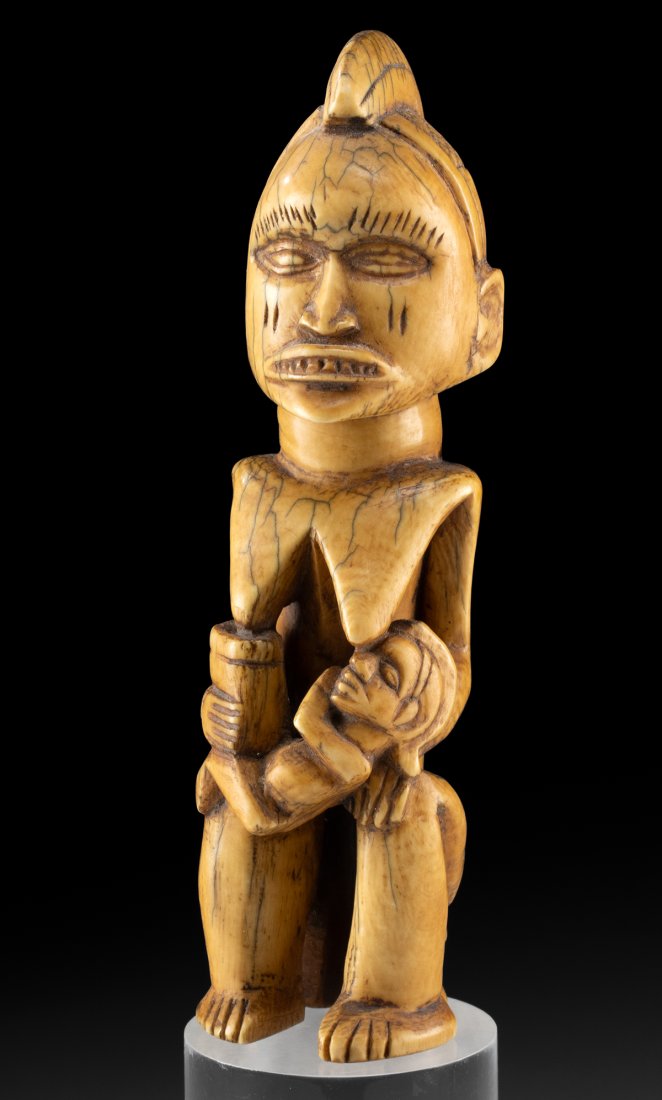 Fine Kongo Elephant Ivory Mother Nursing Child Carving: Central Africa, Democratic Republic of Congo, Kongo culture, ca. 19th century CE. A hand carved elephant tusk ivory carving of a mother breast feeding her infant, with a cup in one hand and the baby o