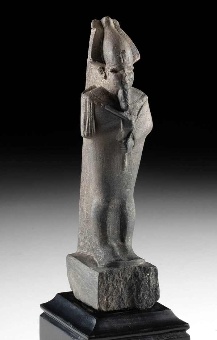 Egyptian Late Dynastic Basalt Figure of Osiris: Ancient Egypt, Late Dynastic Period, 26th to 31st Dynasty, ca. 664 to 332 BCE. A figure of Osiris, god of the underworld, that is hand-carved from black basalt. The deity stands in mummiform atop an i