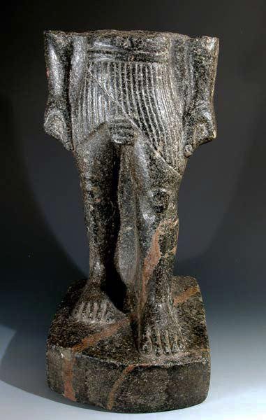 An Egyptian Granite Torso - The Striding King: Egypt, New Kingdom, 1550-1070 B.C. Carved from a single piece of striated granite stone / granodionte, figure depicts the lower torso of a high official or king wearing a heavily-pleated kilt. On the