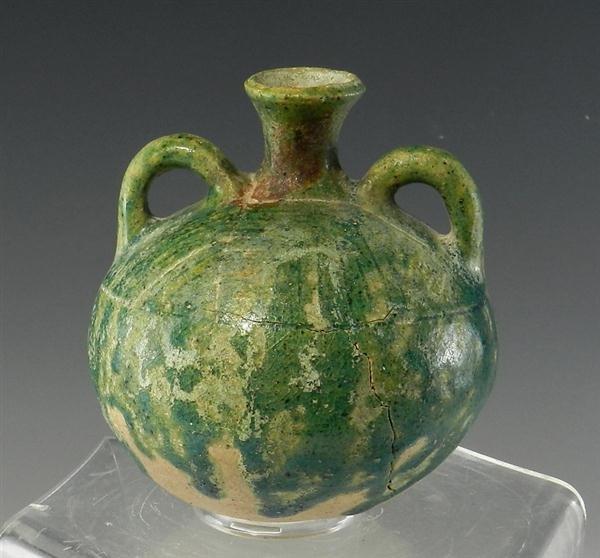 An Islamic Green-Glazed Canteen Vessel: From the ancient Near East, dating from the 12th - 13th century AD. Terracotta vessel with bulbous body and flared spout with handles on either side; slipped in a beautiful green glaze, except for bot