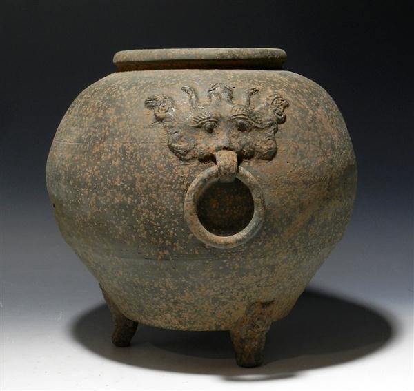 A Han Dynasty Greyware Pottery Vessel Taotie Masks: China, ca. 206 BC - 220 AD. Pottery vessel sits on three anthropomorphized feet, body balloons out up the body, then slightly inward at rim. Handles are Taotie (Chinese ritual masks) with rings throug