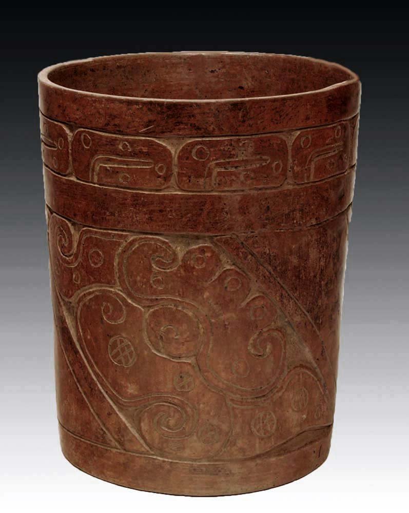 A Mayan Carved Brownware Cylinder: Pre-Columbian, Mexico, Ca. 600 to 900 AD. Carved burnished clay vessel incised with heads of serpents on the diagonal and a PSS under rim. 7"H. Provenance: Ex-Art for Eternity, New York, NY, ex-privat