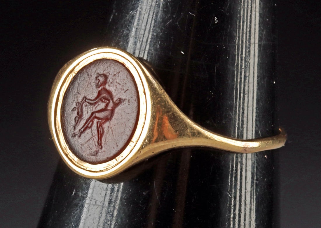 Published Roman Intaglio Satyr / Cupid (in Gold Ring): Roman, Republic Period, ca. 1st century BCE; Europe, Neoclassical period, ca. 19th to early 20th century CE. A beautiful 67.5% gold ring setting displaying a hand-carved carnelian intaglio of planar f