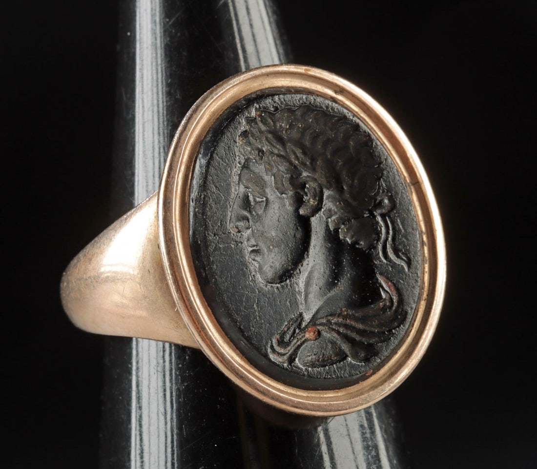 Neoclassical Ring w/ Glass Intaglio of Laureate Man: Western Europe, England / France, ca. 18th century CE. A wearable gold-copper alloy ring inlaid with a black glass intaglio deeply engraved with the profiled bust of a man and set in a gold-copper all
