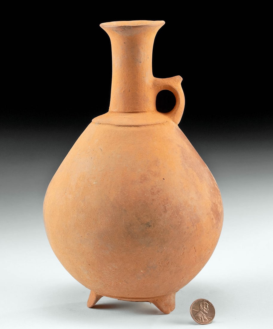 Ancient Iranian / Amlash Redware Footed Jug: Ancient Near East, northwestern Iran, Amlash, ca. 1200 to 800 BCE. A hand-built pottery pitcher with a carinated body, a ring-form shoulder, a petite handle with a protruding thumb rest, and a tall ne