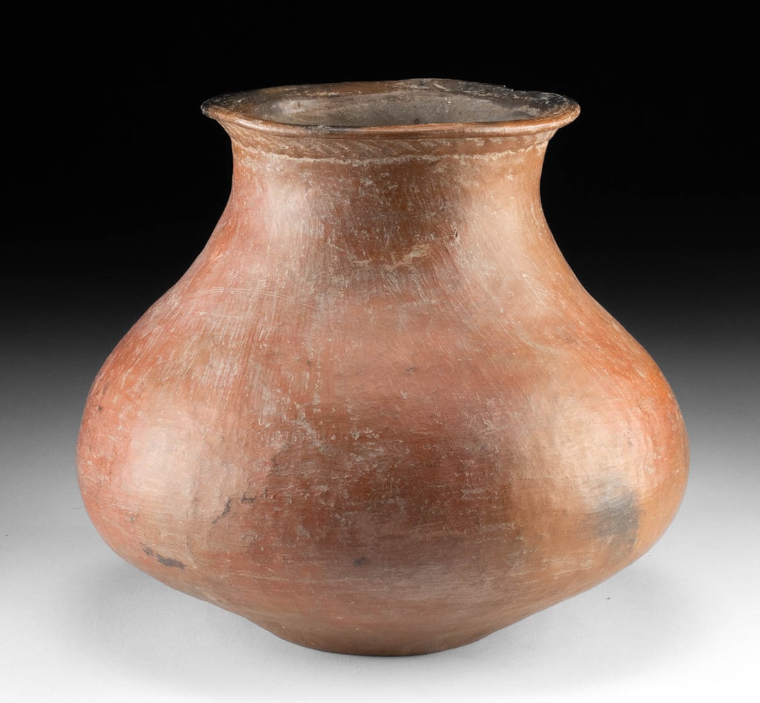 Impressive Colima Redware Pottery Jar: Pre-Columbian, West Mexico, Colima, ca. 300 BCE to 300 CE. An elegant redware jar boasting a rotund body that slopes upward to an attenuated neck and flared rim. An applied band of impressed diagonal