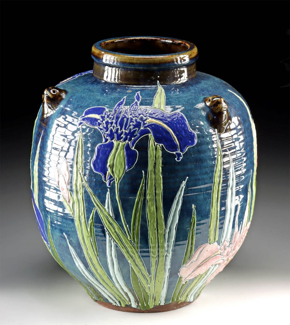 1920s Japanese Showa Glazed Jar w/ Irises & Lion Heads: East Asia, Japan, Showa period, ca. 1920s to 1930s CE. A gorgeous stoneware jar featuring a voluminous form with a folded rim, a brief neck, and an apple-shaped body, all sitting upon a circular foot.